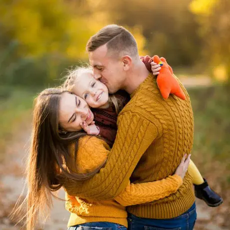 a mom and a dad happy hugging their little kid