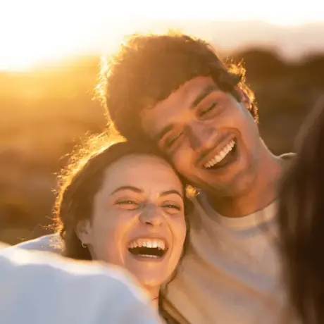 a happy couple hugging and smiling together with sunset backlighting